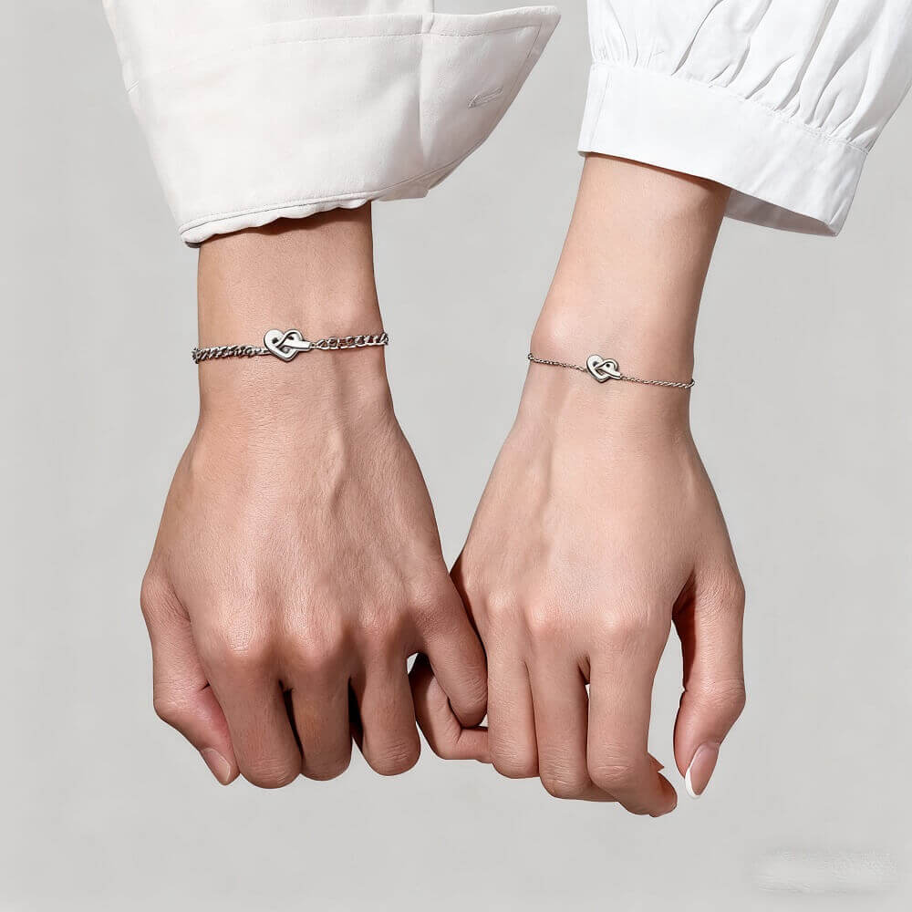 Deux mains portant des bracelets nœud cœur assortis